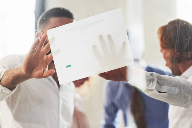 las personas que trabajan en la oficina y discuten algunos detalles de negocios utilizando información sobre papel - short working long human hand fotografías e imágenes de stock