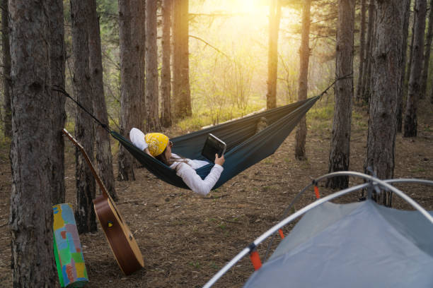 istock Lazy Afternoon Outdoors. Young Woman Tourist Using her Digital Tablet while Swinging in the Hammock. Camping in the Nature. 1141869349