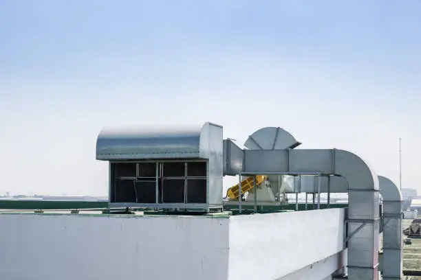 Photo of roof top building air ventilation flow system vent pipe fan HVAC.