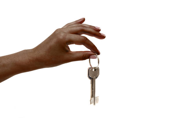 istock African female hand holds keys on white background. 1141877014