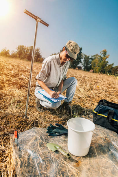 istock Agronomist Writing In Paper While Crouching On Field 1141879907