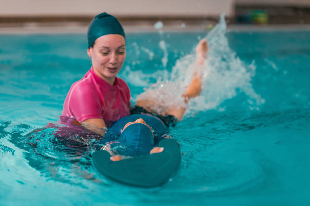 istock Boy Learning To Swim In Pool With Teacher 1141880046