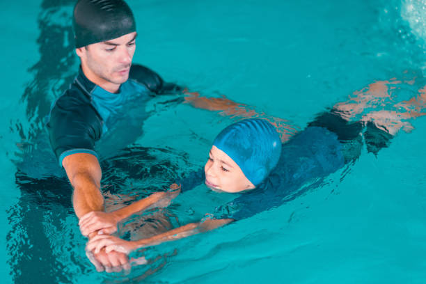 istock Boy Learning To Swim In Pool With Teacher 1141880064