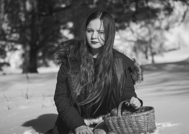 Mid-age woman wearing thick winter hat and scarf holding a tripod. Non-urban winter background. Half-figure portrait