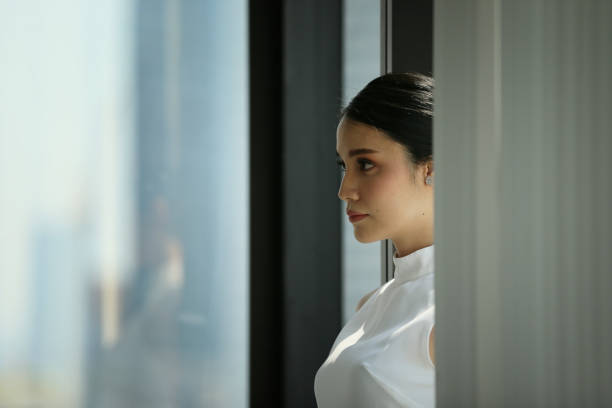 istock Businesswoman Looking Away While Standing Against Window At Office 1141881592