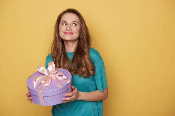 mezza lunghezza di ragazza felice che tiene un regalo in braccio al chiuso - hair bow shirt bow one young woman only foto e immagini stock