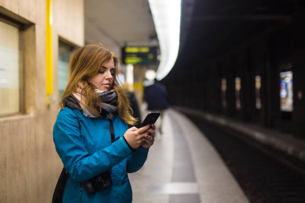 Young woman using mobile phone in a subway. About 25 years old, Caucasian female.