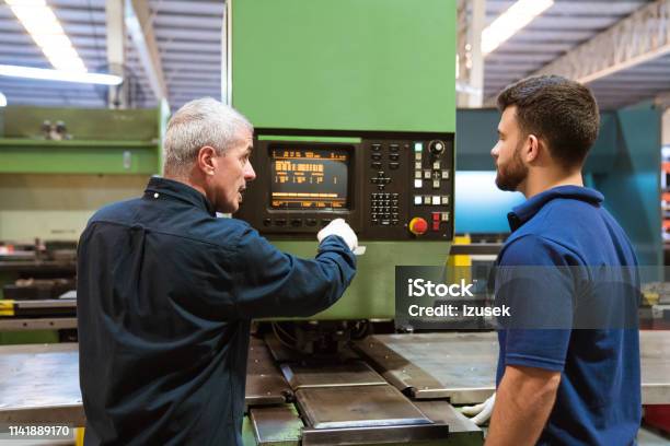 Instructor Teaching Trainee In Factory Stock Photo - Download Image Now - Casual Clothing, Device Screen, Factory