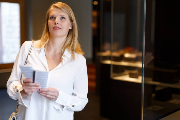 istock Female visitor with guide book looking at exhibition 1141890431