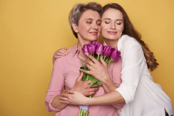 beautiful caucasian girl is hugging her mother while posing for camera - bouquet mothers day tulip flower imagens e fotografias de stock