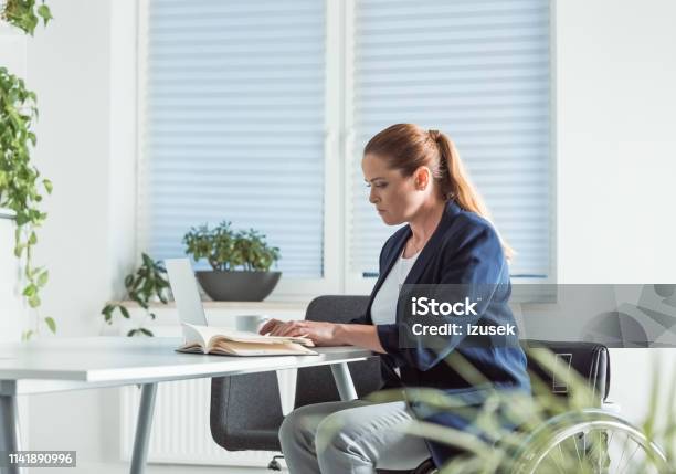 Disable Businesswoman Reading Book At Desk Stock Photo - Download Image Now - Business, Business Person, Desk