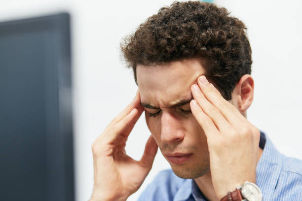 istock Young man working on computer rubs his head tiredly 1141891186