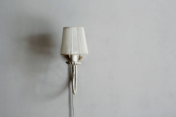 Lamp sconces on a gray wall with shadows in the interior design room with free copy space for text