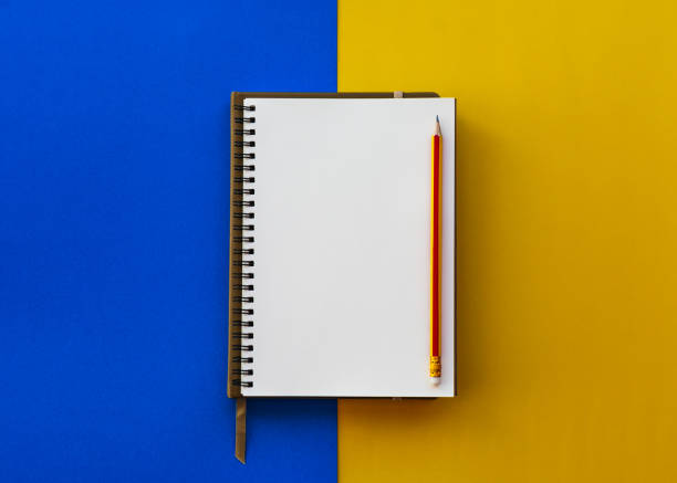 istock Blank white notepad with pencil isolated on two tone yellow and blue background. 1141901958