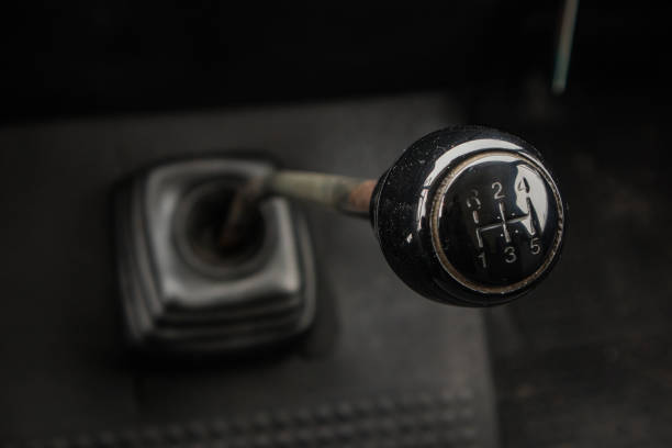 A gear stick of an old van. Visible knob, stick and rubber boot on the floor.