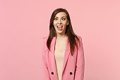 Portrait of crazy funny loony young woman in jacket with beveled eyes showing tongue isolated on pastel pink wall background in studio. People sincere emotions, lifestyle concept. Mock up copy space.