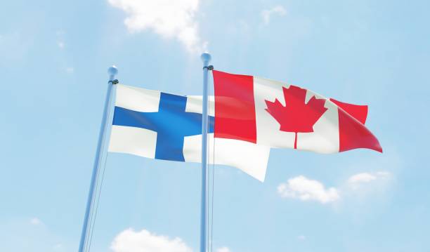 istock Canada and Finland, two flags waving against blue sky 1141904656