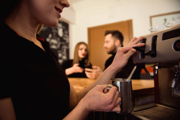 istock Professional female barista holding metal jug warming milk using the coffee machine. 1141904877