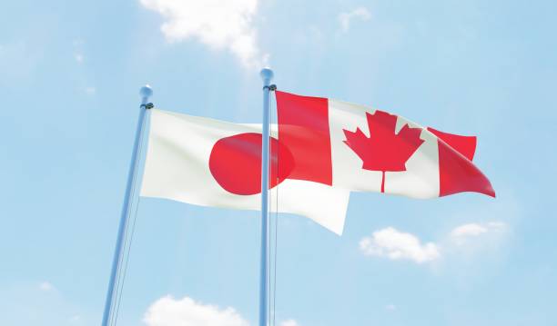 istock Canada and Japan, two flags waving against blue sky 1141904884