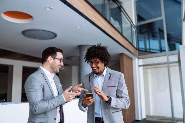 istock Diverse male employees standing in hallway using smart phone 1141905093