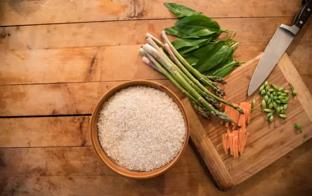 Preparing Rice With Ramson, Asparagus and Carrots on Wooden Table.