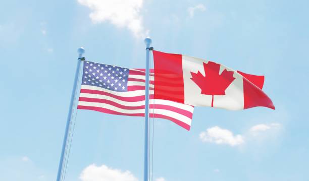istock Canada and USA, two flags waving against blue sky 1141905310