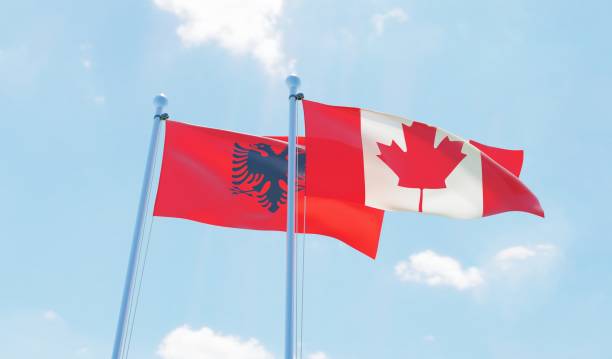 istock Canada and Albania, two flags waving against blue sky 1141905348