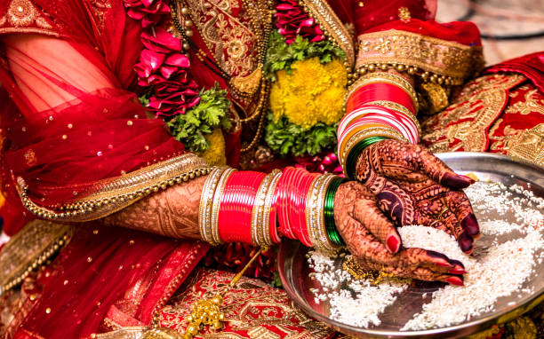 Beautiful Photo of an Indian Bride performing ritual by offering rice to God, in a Hindu Marriage Ceremony of India