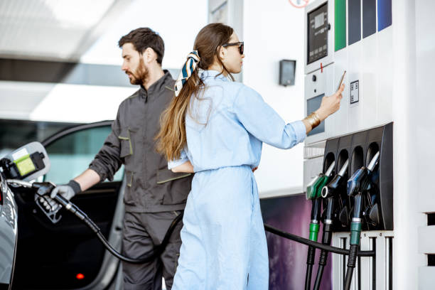 frau zahlt mit telefon an tankstelle - half tank stock-fotos und bilder