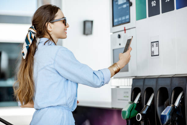 donna che paga con il telefono alla stazione di servizio - gasoline fuel pump women currency foto e immagini stock