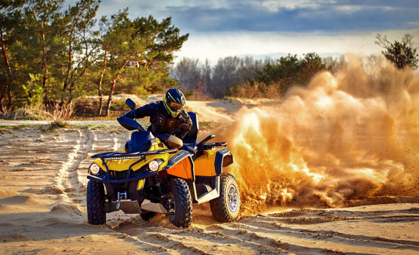 Racing in the sand on a four-wheel drive quad. Racing powerful quad bike on the difficult sand in the summer. quadbike photos stock pictures, royalty-free photos & images