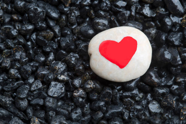 istock Red heart on a white stone with dark stones for background 1141910585