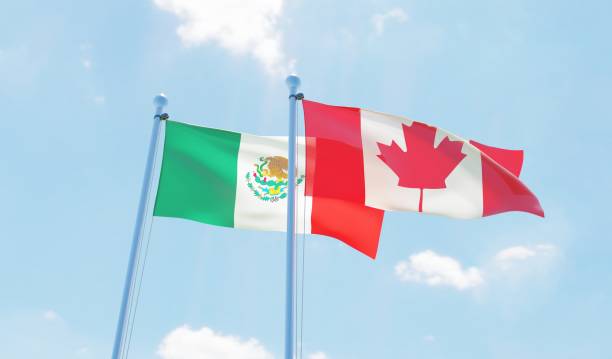 istock Canada and Mexico, two flags waving against blue sky 1141910727