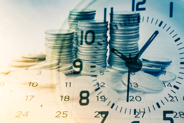 double exposure of rows of coins with clock and calendar for business and finance background stock photo