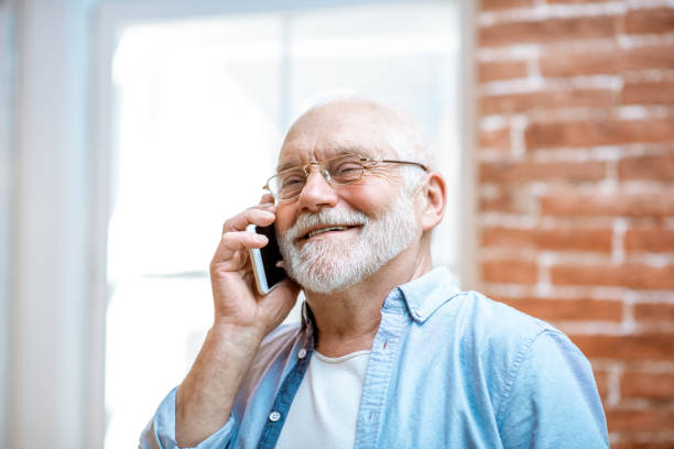 istock Senior man talking with phone at home 1141920502
