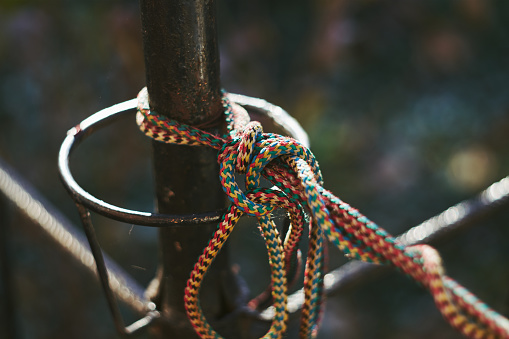 A close-up shot of ropes that have been tied in a knot to a metal pole.