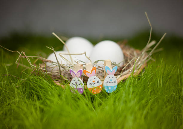 istock Basket decorated with Easter bunnies with white eggs on a green lawn 1141928289