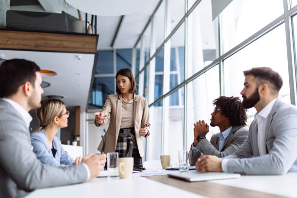 istock Female manager stands addressing team at board meeting 1141930263