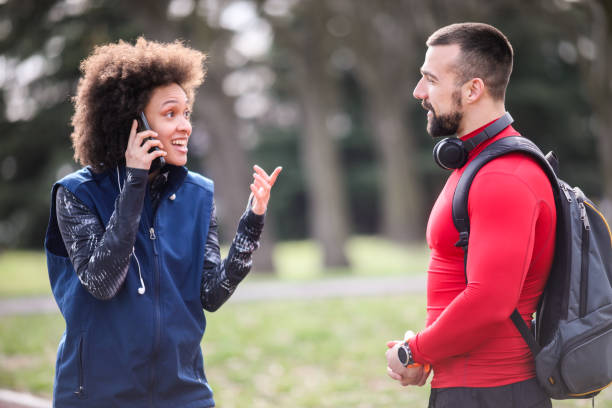 istock Active athletic young woman having a conversation on a mobile phone while standing on a running track with her partner 1141941462
