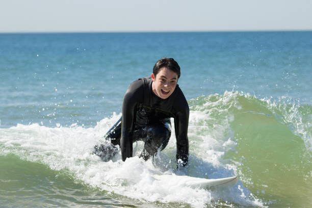 istock Excited young man standing up on surfboard in sea 1141945399