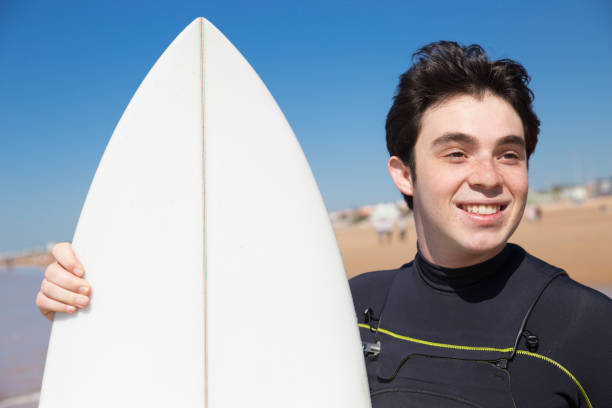 istock Smiling young man with surfboard on sunny beach 1141945459