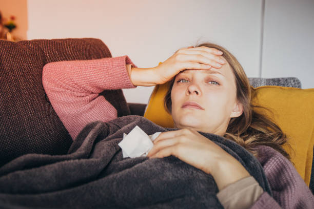 istock Sick woman holding one hand on head, having napkin in another 1141946751