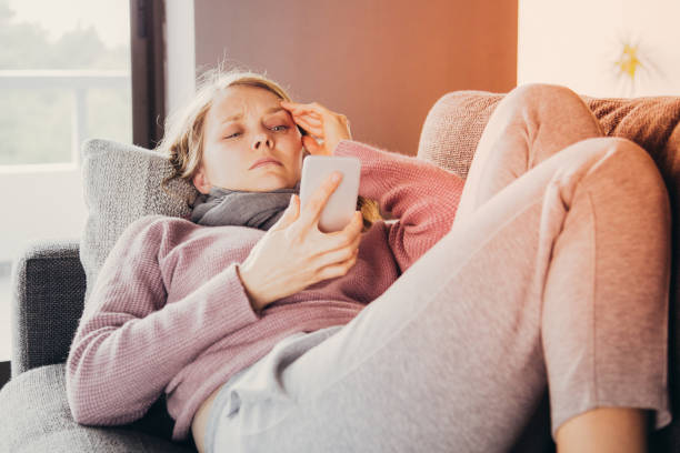 istock Sick woman with scarf around neck, texting on mobile 1141946767