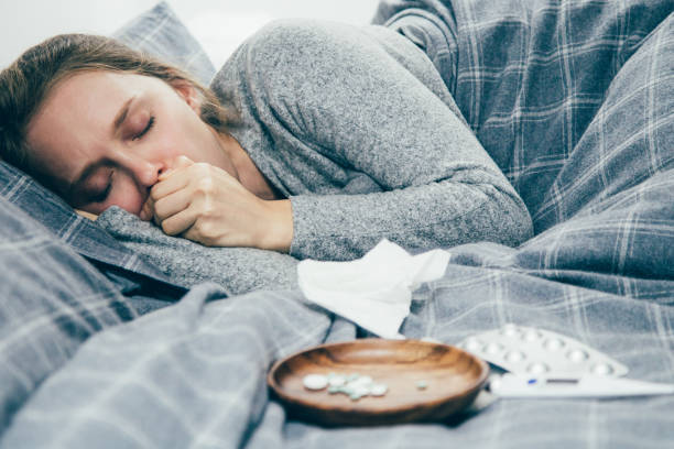 istock Sick young woman lying in bed with closed eyes, coughing 1141947310