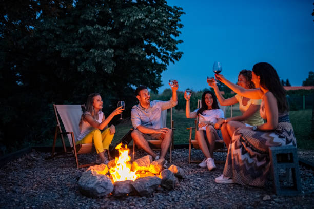istock Group of friends cheering while sitting around the bonfire. 1141947991