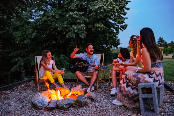 istock Group of friends having fun around the campfire. Playing guitar, singing and drinking. 1141947998