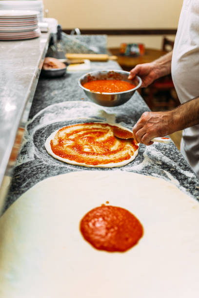 istock Chef preparing the pizza base with tomato sauce. 1141948118