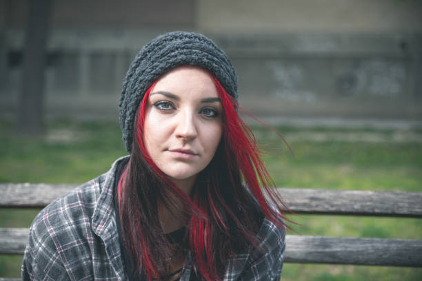 młoda piękna czerwona dziewczyna włosy siedzi samotnie na zewnątrz na drewnianej ławce z kapeluszem i koszulą uczucie niepokoju i depresji po tym, jak stała się bezdomną osobą bliska portret - schoolgirl lifestyles university beautiful zdjęcia i obrazy z banku zdjęć