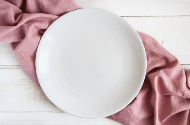 istock White plate on pink napkin 1141953539