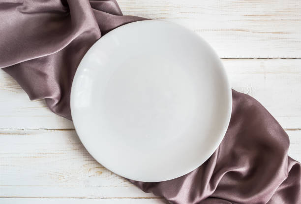 istock White plate on checkered lilac satin napkin 1141953541